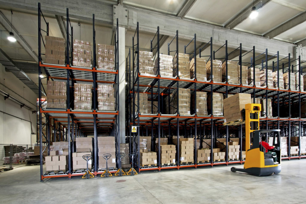 Inside a section of an ambient warehouse, showing a forklift truck manoeuvring a palleted SKU from racking, to the facility floor.