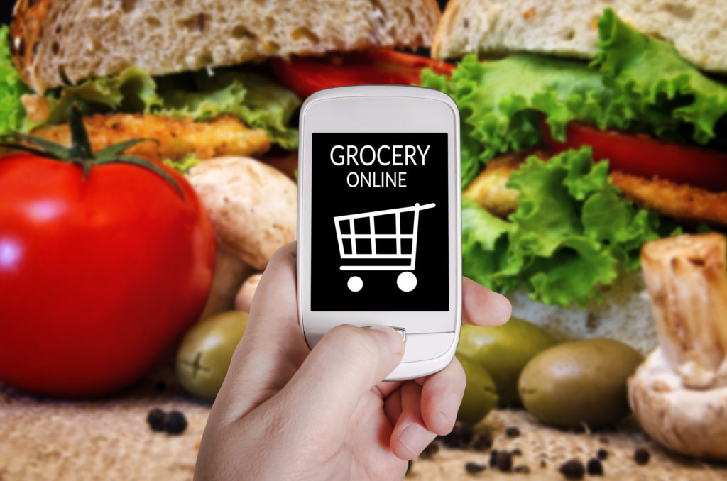 Hand holding smart phone on blurred sandwich image background - shopping online